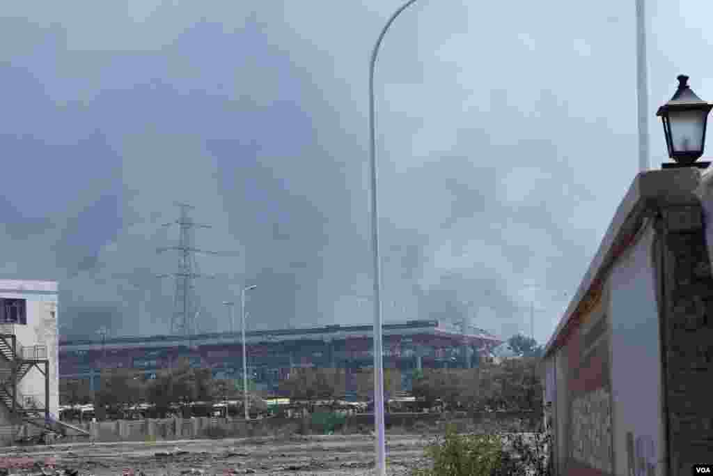 天津爆炸事故现场,核心爆炸区周围多座居民楼窗户被震碎,高速公路桥梁受损,多辆大货车被炸翻,小汽车起火或被砸,多名当地居民仍逗留在事故现场。(美国之音记者东方拍摄)