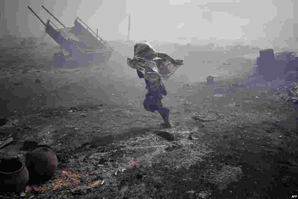 A young woman runs through the burnt huts in the informal camp for displaced people of Faladie in Bamako, April 28, 2020 after a fire broke out. The fire destroyed much of the main camp where more than 1,000 people who fled the violence in central Mali have found refuge.