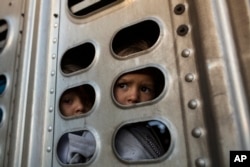 A couple of Central American migrant girls, part of the caravan hoping to reach the U.S. border, get a ride in a chicken truck, in Irapuato, Mexico, Nov. 12, 2018.