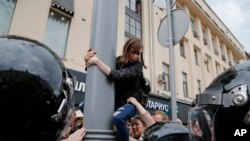 Una manifestante es bajada de un poste por autoridades durante una protesta en Moscú. Monday, June 12, 2017. 