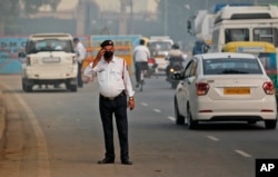 In this Nov. 4, 2019, file photo, a traffic officer wears a pollution mask and clears the irritants from his eyes in New Delhi, India. (AP Photo/Manish Swarup, File)