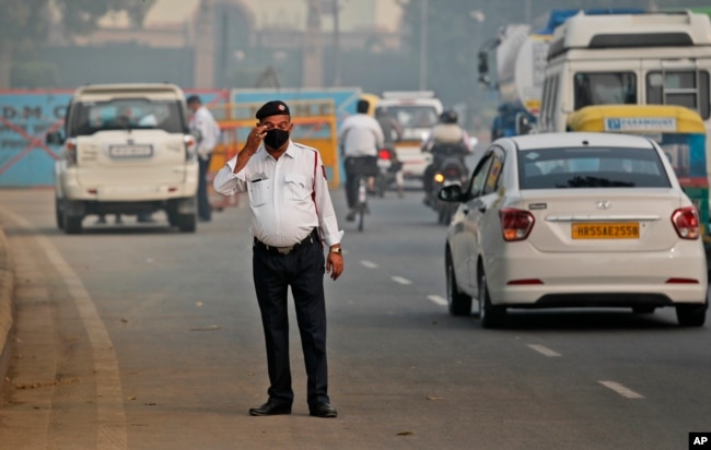 In this Nov. 4, 2019, file photo, a traffic officer wears a pollution mask and clears the irritants from his eyes in New Delhi, India. (AP Photo/Manish Swarup, File)