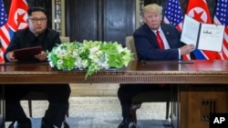 Le président américain Donald Trump brandit le document que lui et le chef de la Corée du Nord, Kim Jong Un, ont signé à la station balnéaire de Capella sur l'île de Sentosa, à Singapour, le 12 juin 2018. 
