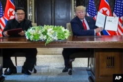 Predsednik SAD, Donald Tramp, drži dokument koji su on i severnokorejskli lider Kim Džong Un potpisali u odmaralištu Kapela na Sentosa ostrvu, 12. juna 2018, u Singapuru.
