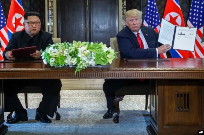 FILE - U.S. President Donald Trump holds up the document that he and North Korea leader Kim Jong Un had signed at the Capella resort on Sentosa Island, June 12, 2018, in Singapore.