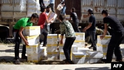 Người dân Syria mang vật phẩm cứu trợ được cung cấp bởi Chương trình Thực phẩm Thế giới của Liên Hiệp Quốc và Trăng lưỡi liềm đỏ Syria ở ngoại ô phía bắc của thành phố Homs, Syria, ngày 25/5/2016.