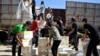 FILE - Syrian men carry aid parcels provided by the U.N. World Food Program and the Syrian Arab Red Crescent in the rebel-held town of Al-Houla, on the northern outskirts of Homs in central Syria, May 25, 2016.