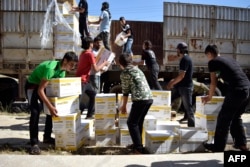 Syrian men carry aid parcels provided by the UN World Food Programm (WFP) and the Syrian Arab Red Crescent in the rebel-held town of Al-Houla, on the northern outskirts of Homs in central Syria, on May 25, 2016.