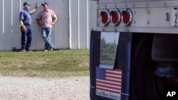 FILE - In this July 12, 2018 photo, farmer Don Bloss, left, talks to his son Mark behind a grain truck on his farm in Pawnee City, Neb. 