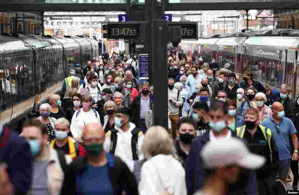 People wearing protective face coverings walk along a platform at King&#39;s Cross Station in London.