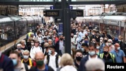 Orang-orang yang memakai masker berjalan di sepanjang peron di Stasiun King's Cross, di tengah wabah COVID-19 di London, Inggris, 12 Juli 2021. (Foto: Reuters)