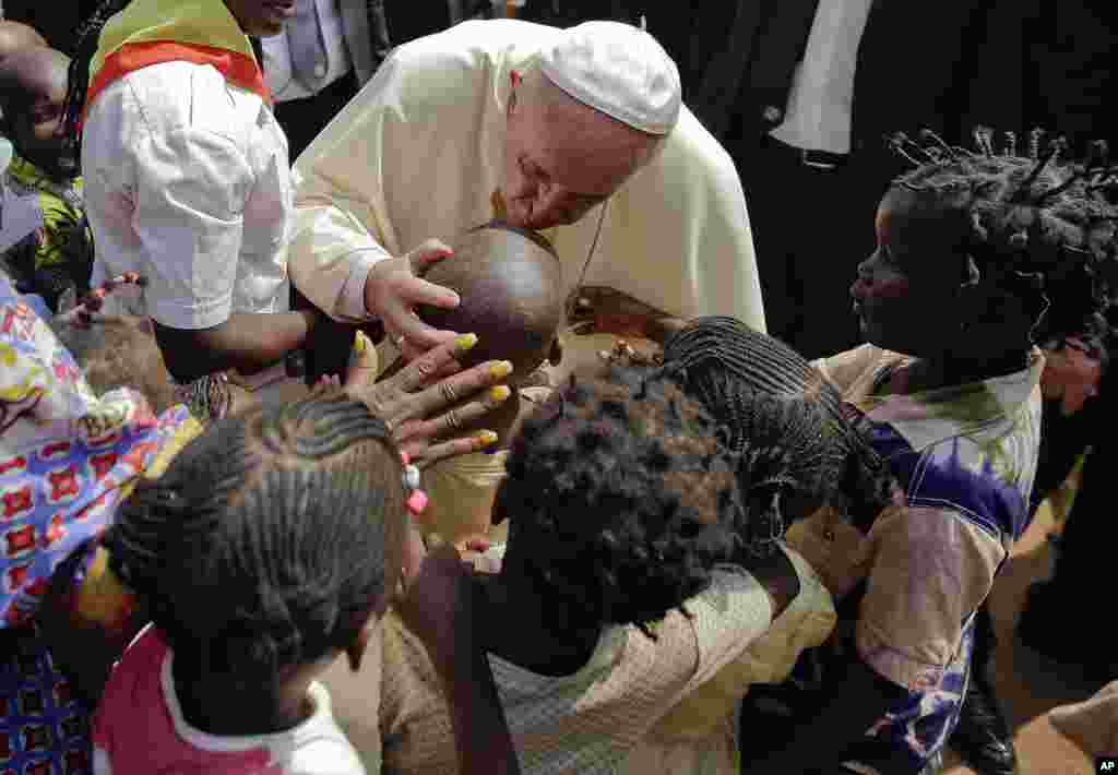 Papa Francis akimbariki mtoto alip[otembelea kambi ya wakimbizi mjini Bangui, Jamhuri ya Afrika ya Kati.