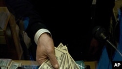 An employee of a currency exchange office displays US dollars next to a 20-euro note on January 6, 2012 in Lyon.