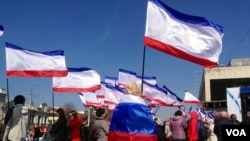Woman at pro-Russian rally, holding a Crimean flag, wrapped in a Russian one, Simferopol, 15 March 2014. (Elizabeth Arrott/VOA).