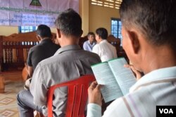 A member of the Grassroots Democratic Party (GDP) read the leaflet shared during the party meeting. The leaflet briefly describes the party policies, including a pathway for rural development, Takeo province, August 9, 2016. (S. Khan for VOA)