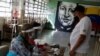 Un mural del fallecido presidente venezolano Hugo Chávez es visto mientras un hombre vota en un simulacro electoral antes de las elecciones regionales de noviembre en Caracas. Octubre 10, 2021.