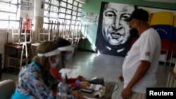 Un mural del fallecido presidente venezolano Hugo Chávez es visto mientras un hombre vota en un simulacro electoral antes de las elecciones regionales de noviembre en Caracas. Octubre 10, 2021.