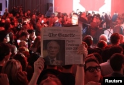 A supporter holds up an old issue of The Gazette newspaper featuring former Prime Minister Pierre Trudeau, father of Liberal Party leader Justin Trudeau, after Canada's federal election in Montreal, Quebec, Oct. 19, 2015.