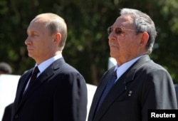 FILE - Russian President Vladimir Putin (L) stands next to Cuba's President Raul Castro as they attend a wreath-laying ceremony at the Soviet Soldier monument in Havana, July 11, 2014.