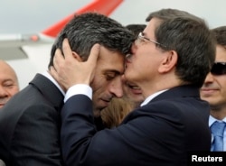 Turkish Prime Minister Ahmet Davutoglu (R) kisses Turkish Consul General of Mosul Ozturk Yilmaz on the forehead during a welcoming ceremony at Esenboga airport in Ankara, Sept. 20, 2014.