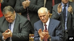 Greek Prime Minister George Papandreou (R) and Finance Minister Evangelos Venizelos applaud after winning a vote of confidence in the Greek parliament in Athens, Greece, November 5, 2011.