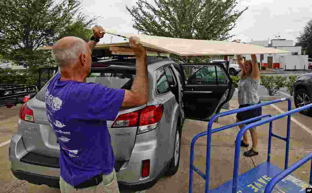 Alex y Cynthia Stone, de Maitland, Florida, colocan hojas de plywood en el techo de su vehículo que usarán para proteger su casa del embate del huracán Irma, que se ha pronosticado golpeará primero en el área de los Cayos al entrar al estado la madrugada del lunes. AP Sept. 6, 2017.