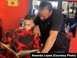 Austin Lopez reads a book to Amir Shalash as he gets his hair cut at Prince Cuts, Lexington, KY