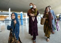 کابل سے ڈیلس ایئرپورٹ پہنچنے والا ایک افغان خاندان ایئرپورٹ سے باہر آ رہا ہے۔ 27 اگست 2021