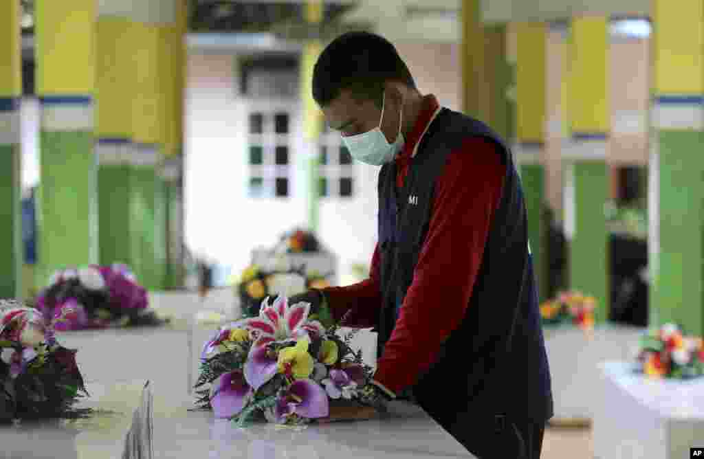 A member of the Indonesia Red Cross prepares coffins for the victims of AirAsia Flight 8501 at the main hospital in Pangkalan Bun.&nbsp; More ships arrived Friday with sensitive equipment to hunt for parts of the plane and the more than 145 people still missing since it crashed into the sea five days ago.