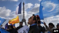 protester of the French Uyghur Community shout slogans and hold flags of East Turkestan