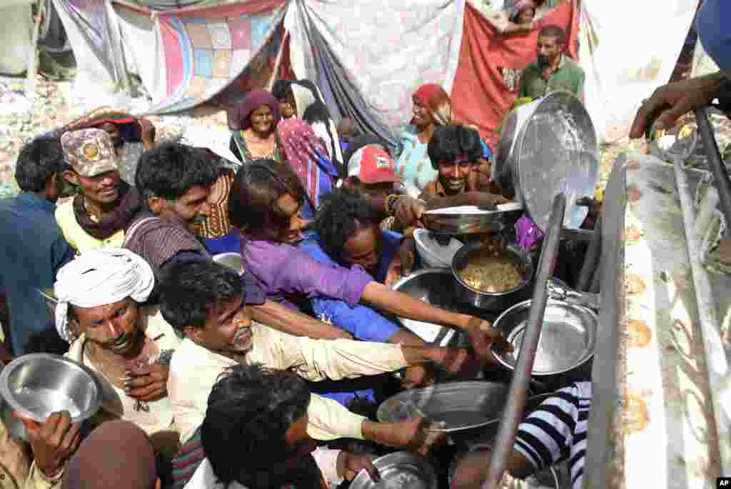 People confined in their homes due to lockdown to contain the coronavirus outbreak jostle to receive free food, in Hyderabad, Pakistan.
