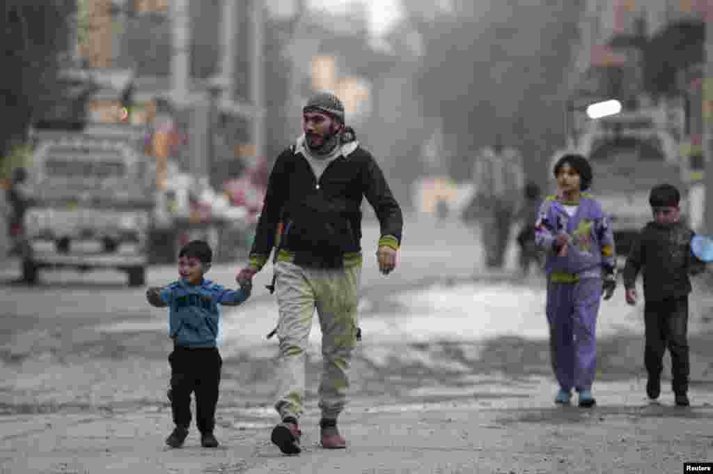 A Free Syrian Army fighter holds the hand of his son as they walk along a street in Deir al-Zor, Feb. 10, 2014.