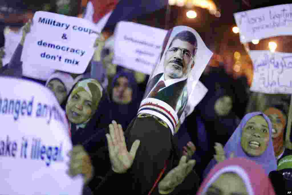 Para pendukung presiden Mesir yang digulingkan, Mohamed Morsi, meneriakkan slogan-slogan sambil membawa poster bergambar Morsi di depan Cairo University (16/7).&nbsp;(AP/Amr Nabil)