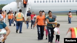 Mujeres y niños salen de un avión estadounidense en el que fueron transportados hasta el aeropuerto Ramón Villeda de San Pedro Sula, Honduras.