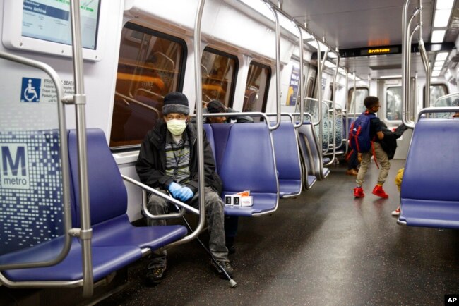 Warga Washington, D.C. menggunakan masker saat naik transportasi umum (dok: AP Photo/Carolyn Kaster)