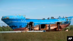 FILE - The wrecked fishing boat that capsized and sunk on April 18, 2015, off the coast of Libya, lies outside a NATO base in the Sicilian town of Mellili, Italy, Oct. 8, 2016.