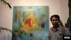 Chhim Sothy, a Cambodian artist, stands in front of his painting at the Plantation Hotel, Phnom Penh, Cambodia, on June 25, 2015.