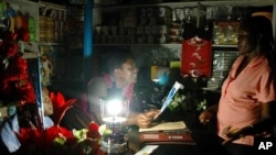 Ugandan women chat in a shop lit by a paraffin lamp in the capital Kampala (file photo)