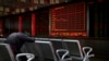 Seorang investor tertidur depan layar elektronik yang menampilkan informasi harga saham di sebuah perusahaan pialang di Beijing, China, 17 September 2018.