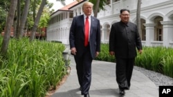 Le président américain Donald Trump et le dirigeant nord-coréen Kim Jong Un marchent au sortir d’un déjeuner à l’hôtel Capella sur l'île de Sentosa à Singapour, le12 juin 2018 (AP Photo/Evan Vucci).