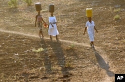 FILE - Women carry water for domestic use from the Limpopo river to their homes in the Salani Village, Mozambique, September 2005.