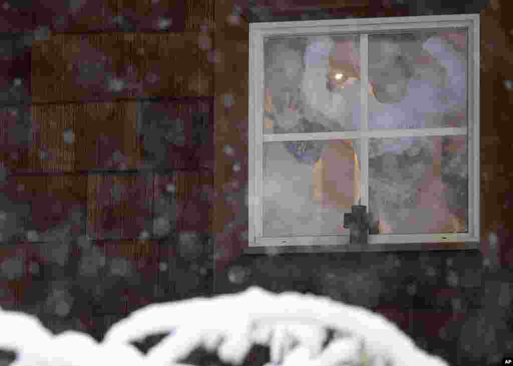 Eden Allen, 3, left, and Josiah Allen, 8, look out their window as a blanket of snow covers the front yard of their home following an early morning snowstorm, in Brandon, Mississippi.