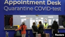 People wait in front of an "Appointment Desk" for quarantine and COVID-19 test appointments inside Schiphol Airport, after Dutch health authorities said that 61 people who arrived in Amsterdam on flights from South Africa tested positive for COVID-19, in 