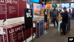 FILE - Customers debate on a television selection at Best Buy, Nov. 26, 2021, in Indianapolis. A key inflation indicator was up 5.8% over last year, the Commerce Department said on Jan. 28, 2022.. 