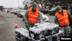 Michigan National Guard members distribute water to a line of residents in their cars in Flint, Michigan, Jan. 21, 2016. 
