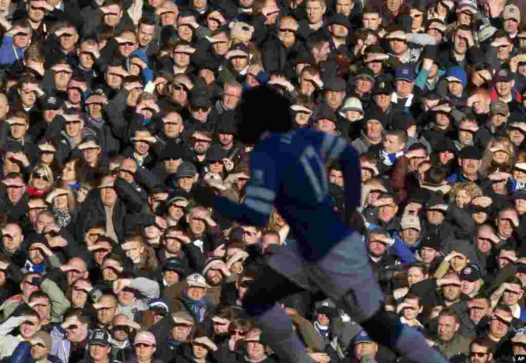 Supporters shield their eyes from the sun as Everton play Southampton during the English Premier League soccer match at Goodison Park Stadium, Liverpool, England.