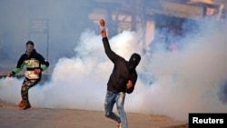 A demonstrator hurls a stone amidst smoke from tear gas fired by Indian policemen during a protest in Kashmir, in Srinagar, Jan. 13, 2018. 