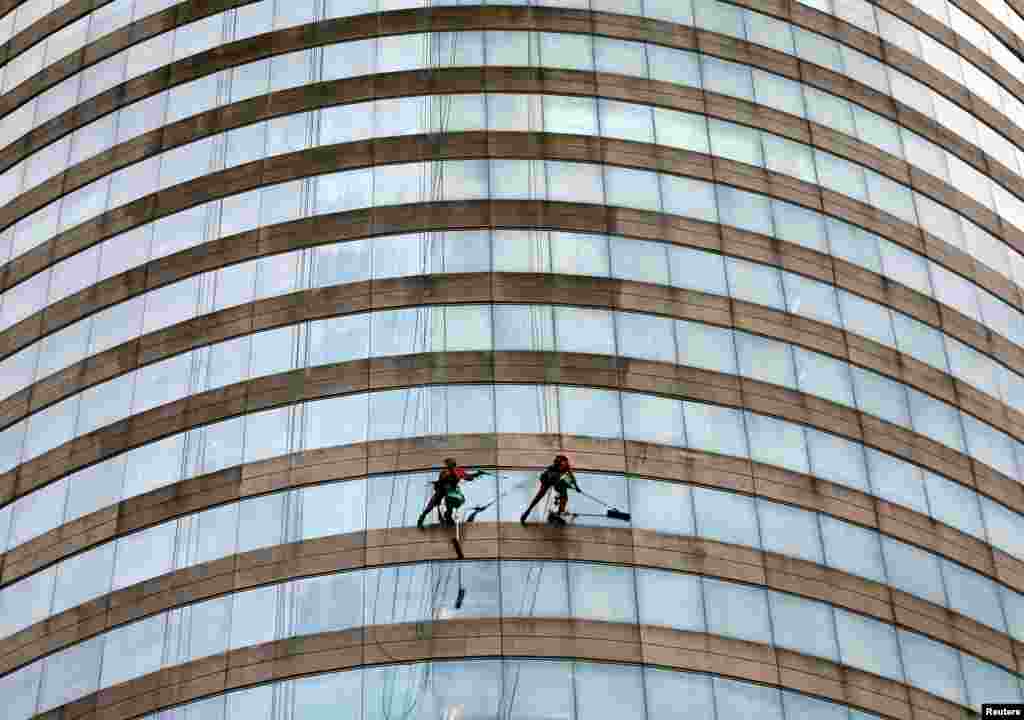 Dua pekerja membersihkan kaca di gedung World Trade Center di Kolombo, Sri Lanka.