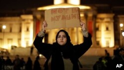 A woman holds up a sign at a vigil for the victims of Wednesday's attack, at Trafalgar Square in London, March 23, 2017. The Islamic State group has claimed responsibility for an attack by a man who plowed an SUV into pedestrians and then stabbed a police officer to death.