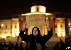 A woman holds up a sign at a vigil for the victims of Wednesday's attack, at Trafalgar Square in London, March 23, 2017. The Islamic State group has claimed responsibility for an attack by a man who plowed an SUV into pedestrians and then stabbed a police officer.